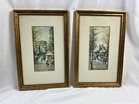 Both framed lithograph prints showing two different Paris scenes by Delarue next to each other.