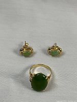 Ring and earrings set displayed on white background, ring front center with earrings behind