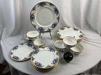 Group shot of eight dinner plates, eight bread plates and six coffee cups with a 3" green apple for scale.