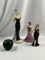 Full view photo showing all three figurines and a green apple for size reference.