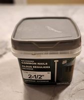 Plastic container labeled Hillman galvanized common nails, size 2-1/2 inch, 1.5 kg (approx. 334 nails)