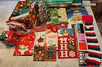 Wide view of all wrapping paper, boxes, bows, gift bags, and stocking arranged on table