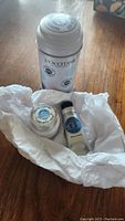 Photo of three L'Occitane skincare products wrapped in white tissue paper on wood surface.