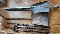 Full view of fireplace tools showing two copper shovels and two twisted iron pokers, one shovel featuring a fleur de lis design.