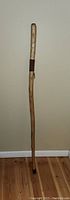Full view of the walking stick, showing its length and natural wood finish.