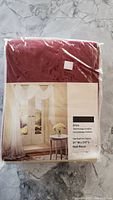 Photo of the scarf drape curtain folded in packaging showing the product name Erica, color red, and dimensions 51" W x 216" L.