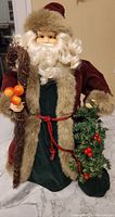 Full body image of Santa Claus decoration showing robe, fur trim, staff with berries, and wreath