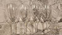 Set of four clear acrylic wine glasses placed upright on a marble surface.