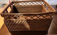 Front and side view of the rectangular wicker basket showing the woven pattern and the handle.