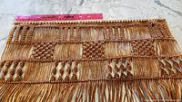 Overall view of the woven wall hanging including ruler for size reference, showing intricate patterns and natural fiber textures.