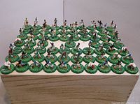 Wide angle photo showing an array of approximately 50 colorful plastic MLB baseball player figures, each mounted on a green circular base with player details. Figures pose in baseball action stances.