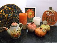 Overall set of assorted fall decor items including glass pumpkins, battery operated candles, decorative fan, teapot, floral art, and pumpkin sign.