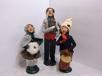Three Byers Choice Carolers figurines together, showing full-body view including attire and bases.