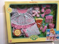 Photo of the full Cabbage Patch Kids Slumber Party set in original box showing dress, bear, pizza toy, hair accessories and other components.