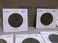 Photo showing multiple Victorian era English coins dated 1887, 1892, 1888, 1890 in white cardboard holders in front of a boxed 1965 Fourth Edition English Coins book.