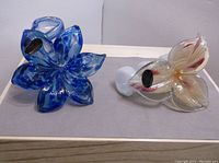 Two Murano glass flowers displayed on a flat surface, showing both flowers side by side and their overall shape and color.