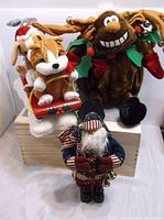 Three Christmas plush holiday figures: reindeer, sleigh with dogs, and Santa figure