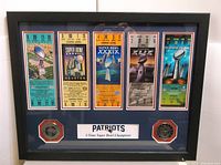 Framed collection of five replica Super Bowl tickets for Patriots' wins, with two medallions mounted on blue matting inside a black frame