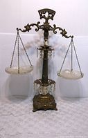 Front view of vintage accurate cast balance scale showing glass plates, hanging chains, and decorative crystal beads.