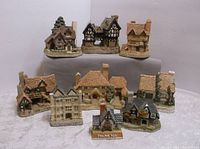 Nine vintage miniature houses displayed on tiered cloth with various English cottage and Tudor styles plus one large manor house