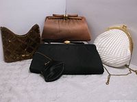 Four handbags and clutches arranged on a flat surface showing all pieces.
