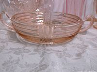 Close-up of round ribbed pink glass dish showing small chip on rim