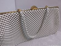 Close-up of white mesh bead exterior and gold-tone clasp closure on the purse.