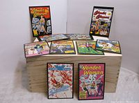 Full lot of 10 DC Comics Wonder Woman cover postcards displayed on wooden box, showing variety of cover art styles and backgrounds.