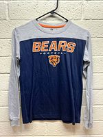 Front view of the youth long sleeve shirt showing the Chicago Bears football text and logo on navy blue body with grey sleeves.