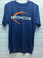 Front view of navy blue Denver Broncos Nike shirt with orange and white screen print of football arc and Broncos text.