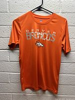 Front view of orange Denver Broncos shirt with team branding on chest.