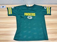 Front view of the Green Bay Packers youth football jersey laid flat on a wooden surface.