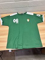 Front view of green women's Irish soccer jersey, size 9-11, showing white number '06' and Irish flag patch on chest.