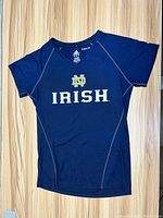 Front view of navy blue youth t-shirt with Notre Dame Irish printed logo and Adidas branding.