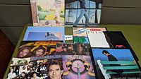 A set of 11 assorted vinyl records including Men at Work, Billy Joel, Toto, and Huey Lewis albums, showing album cover artwork.