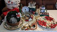 Overview of Christmas ornaments, platters, wreath, and tablecloth stacking on a couch