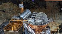 Wide view of the kitchenware lot including copper colander, metallic strainer, bread warmer, cooking timer, and various baking molds and utensils.