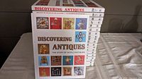 Stack of 20 Discovering Antiques books showing front cover and spines with volume numbers and images of various antiques.