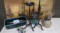 Wide shot showing all items in the lot including paintings, pottery planter, candle holders, oil lamp, bird figurine, and jar.