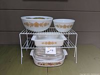 Assorted Pyrex bowls and casserole dish displayed on wire racks to show size and detail