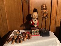 Photo showing all 12 pieces including bartender figurine, female tray bearer doll, and 10 wooden figurative bottle stoppers.