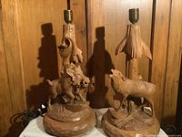 Front view of two carved wooden Black Forest lamps with animal figures and leaf motifs, showing overall condition and size.