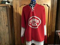 Front view of red Corner Gas hockey jersey on mannequin showing logo and lace-up collar.