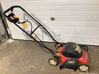 Side view of the Homelite lawn mower showing folding handle, wheels, and electric cord outlet on the deck.