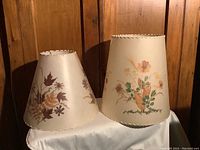 Photo of two Dornbusch lamp shades side by side on a white cloth against wood paneling background