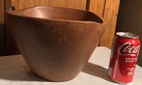 Side view of the teak wooden bowl next to a Coca-Cola can for size reference, showing its smooth surface and wood grain.