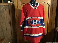Front view of red Montreal Canadiens hockey jersey with team logo across chest.