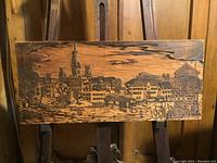 Front of woodblock showing carved relief of buildings and water