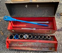 Full view of ratchet, two extension bars inside red toolbox and row of 10 sockets on toolbox tray.