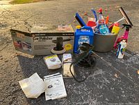 Photo showing entire lot including Black & Decker car polisher with box, bucket with cleaning supplies, antifreeze bottle, ice scrapers, and polishing bonnets in packaging.